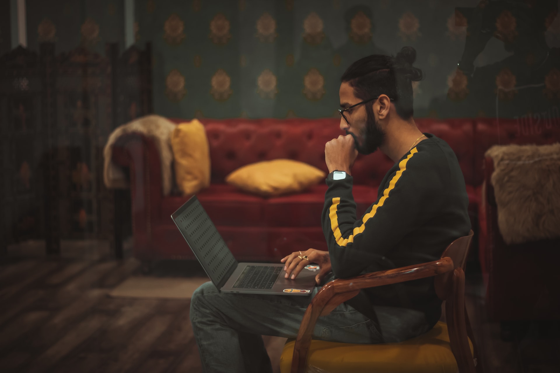 Knowledge Worker with man bun thoughtfully looking at laptop